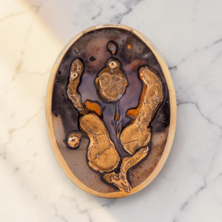 Reserved Grace vintage 1985 Norwegian hand-painted ceramic brooch with abstract gold luster glaze on grey background.