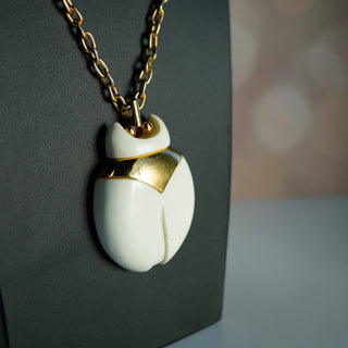Reserved Grace vintage Crown Trifari beetle pendant necklace featuring a white lucite body and gold-tone metal frame.