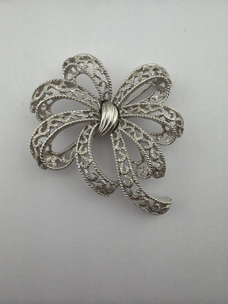 Reserved Grace vintage silver-tone Trifari bow brooch with intricate filigree lacy loops and a polished center band.