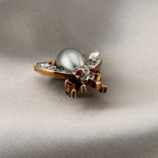 Reserved Grace vintage Trifari insect brooch with a silver-gray cabochon body, clear rhinestones, and red accents.