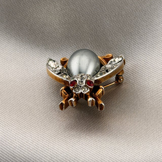 Reserved Grace vintage Trifari insect brooch with a silver-gray cabochon body, clear rhinestones, and red eyes.