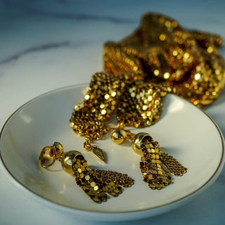Reserved Grace vintage Whiting & Davis gold mesh necklace and tassel clip earring set on a white dish
