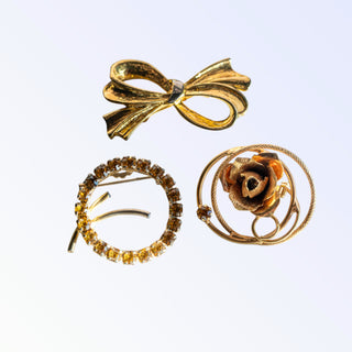 Three gold brooches on a white background